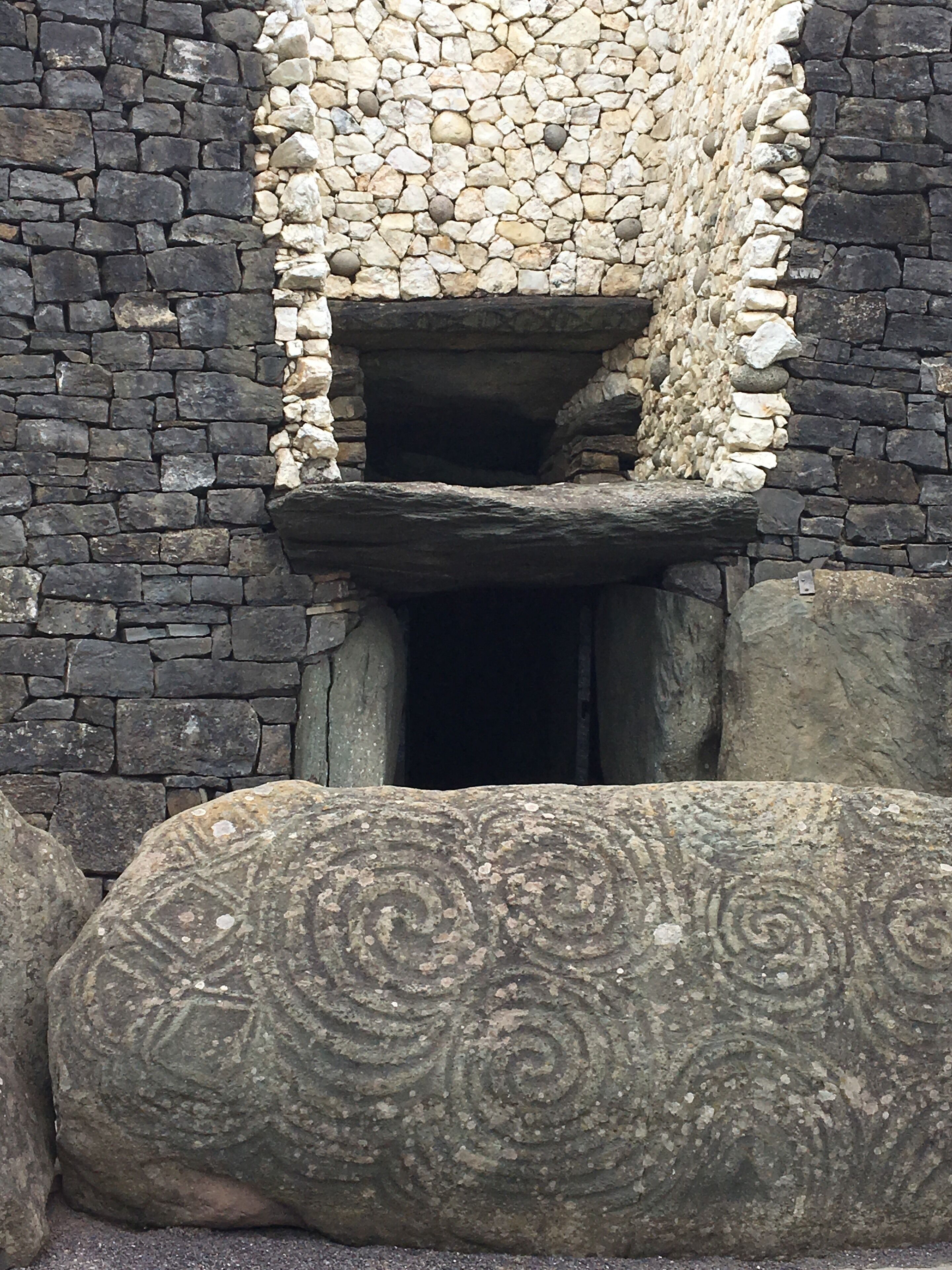 Uma estrutura de pedra com uma abertura retangular e uma laje decorativa em frente.
