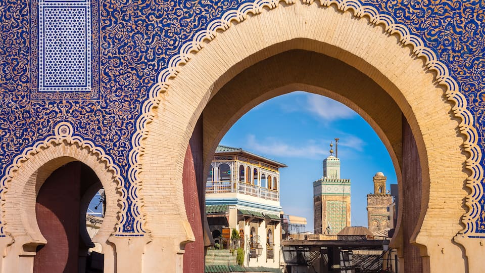 A historic building with intricate blue and white tile work, a large archway, and a clear blue sky.