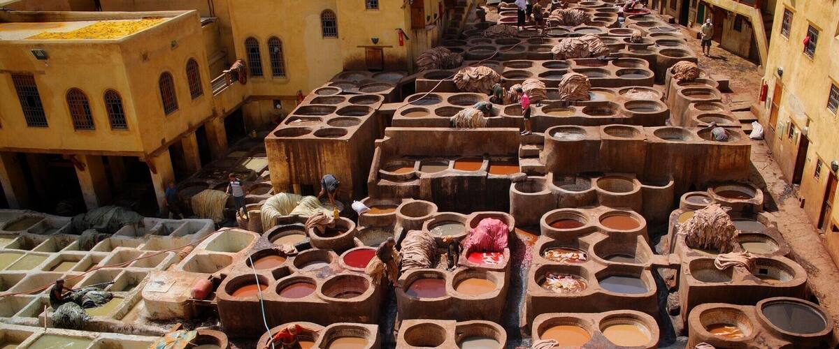 A traditional dyeing area with large vats and workers processing textiles.