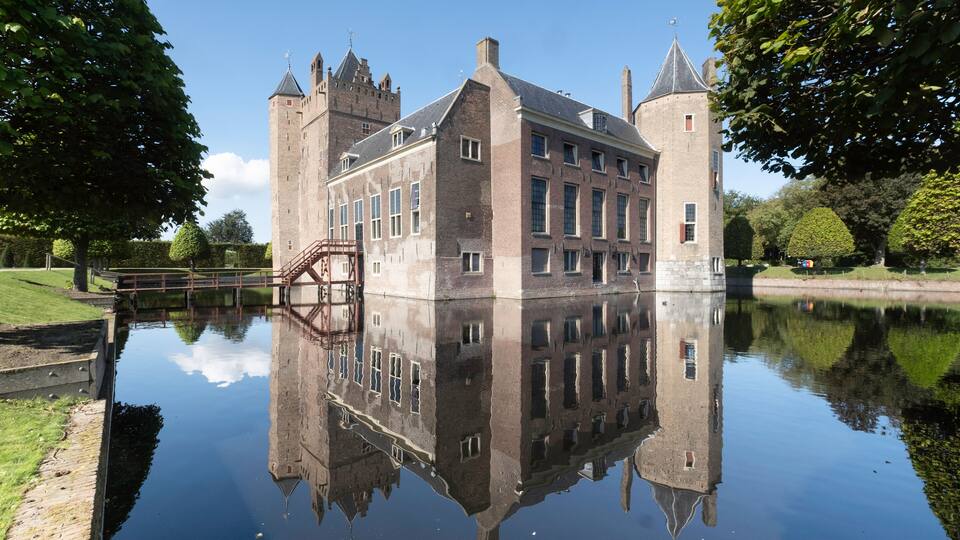 A historic castle with a moat and reflection in the water.