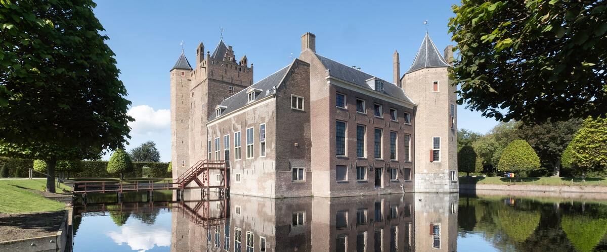 A historic castle with a moat and reflection in the water.
