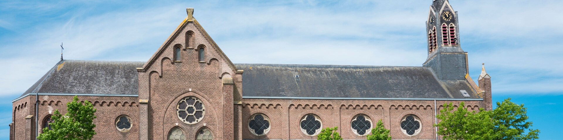 Una iglesia histórica con un campanario destacado y un amplio ventanal circular.