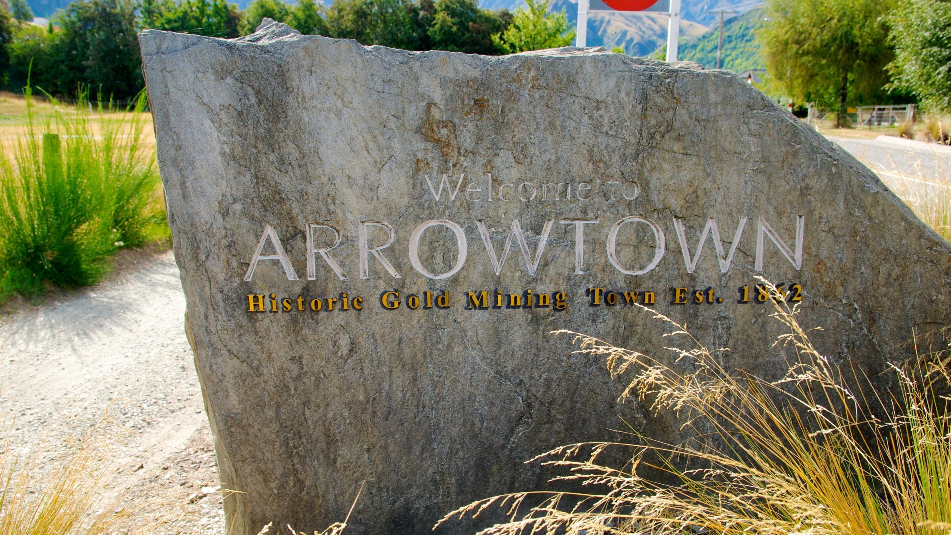 A large stone sign with the text "Welcome to Arrowtown Historic Gold Mining Town Established 1882".