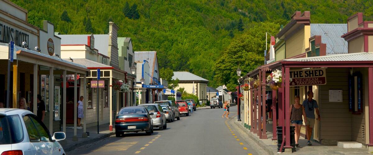 A street lined with shops, including a hotel and a cafe, with cars parked on the side.