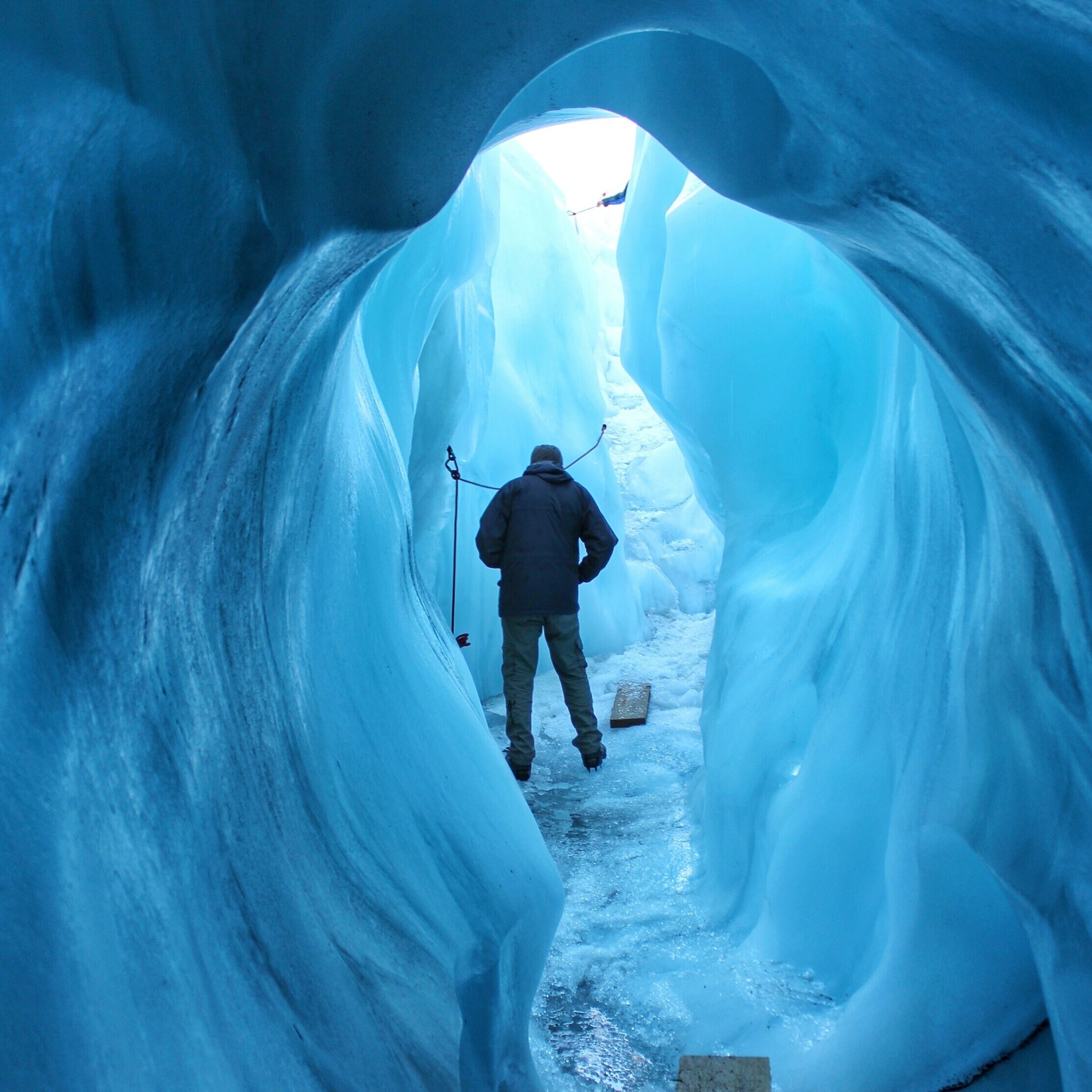 A person walking through a narrow, icy tunnel.