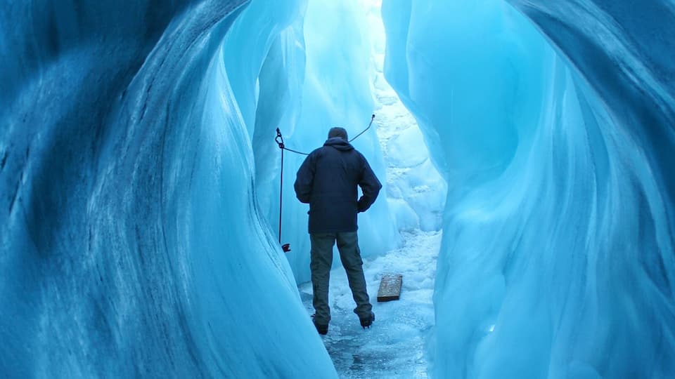 A person walking through a narrow, icy tunnel.
