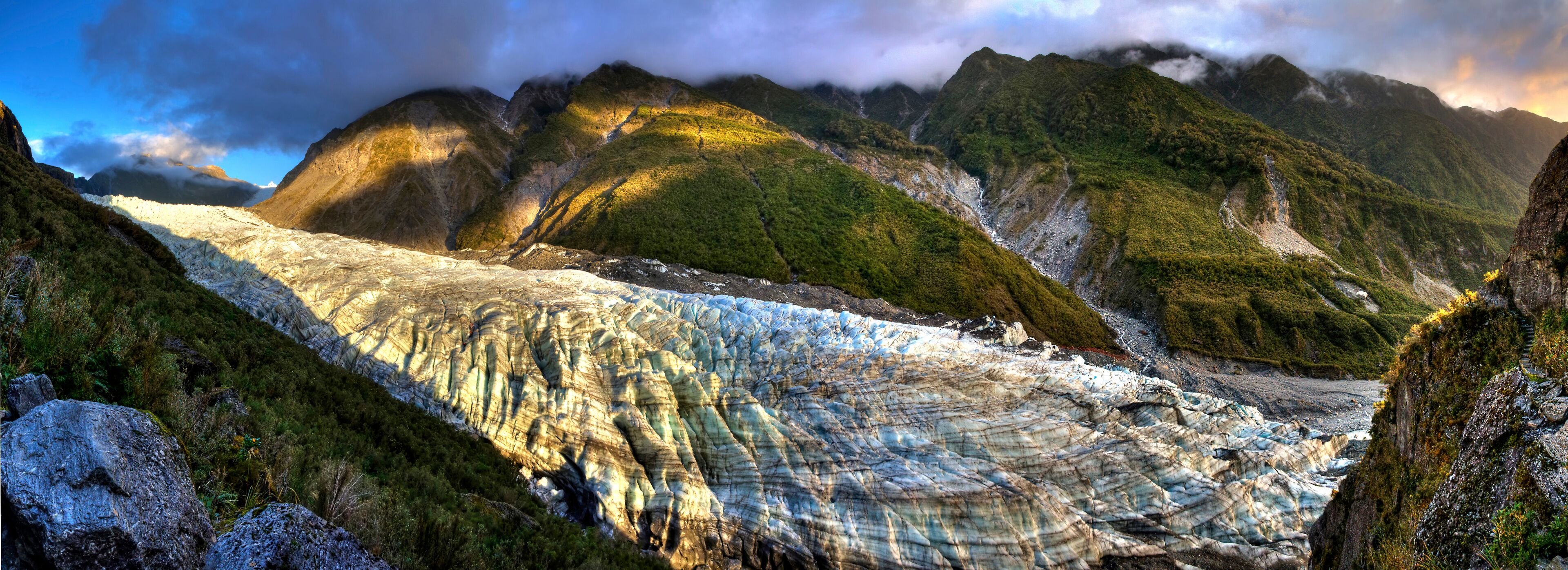 Un glaciar con acantilados rocosos empinados y una vegetación verde exuberante.