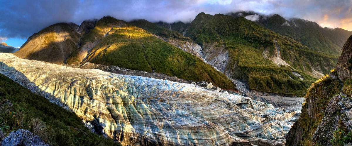 Un glaciar con acantilados rocosos empinados y una vegetación verde exuberante.