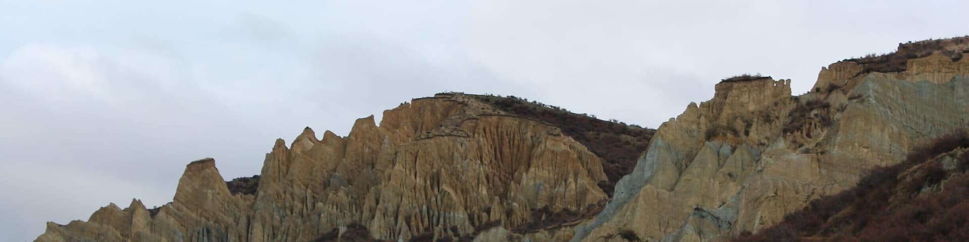 amazing clay cliffs between Omarama and Mount Cook - worth the drive off the main road - lots of different colors of clay and the red fruit in the foreground are on the sweet briar rosehip bushes a plant that was introduced to NZ by the settlers