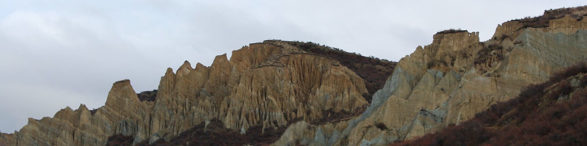 amazing clay cliffs between Omarama and Mount Cook - worth the drive off the main road - lots of different colors of clay and the red fruit in the foreground are on the sweet briar rosehip bushes a plant that was introduced to NZ by the settlers