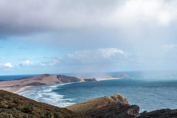 Incoming rain on Te Werahi Beach, Cape Maria van Diemen and Motuopao Island. This view is from New Zealand's most northern point, Cape Reinga. You can walk this beach as part of the Te Araroa trail - a walkway that stems from the most northern point to the most southern point of New Zealand.