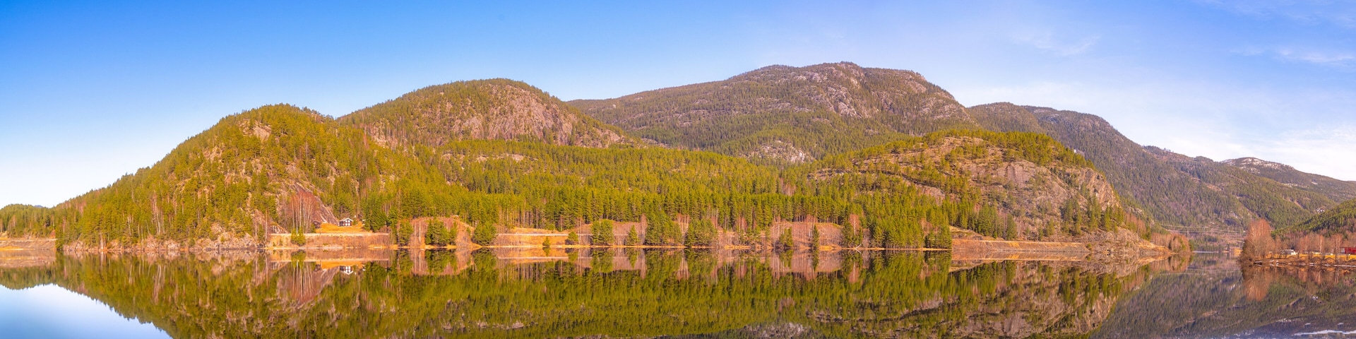 A calm lake reflecting mountains and trees.