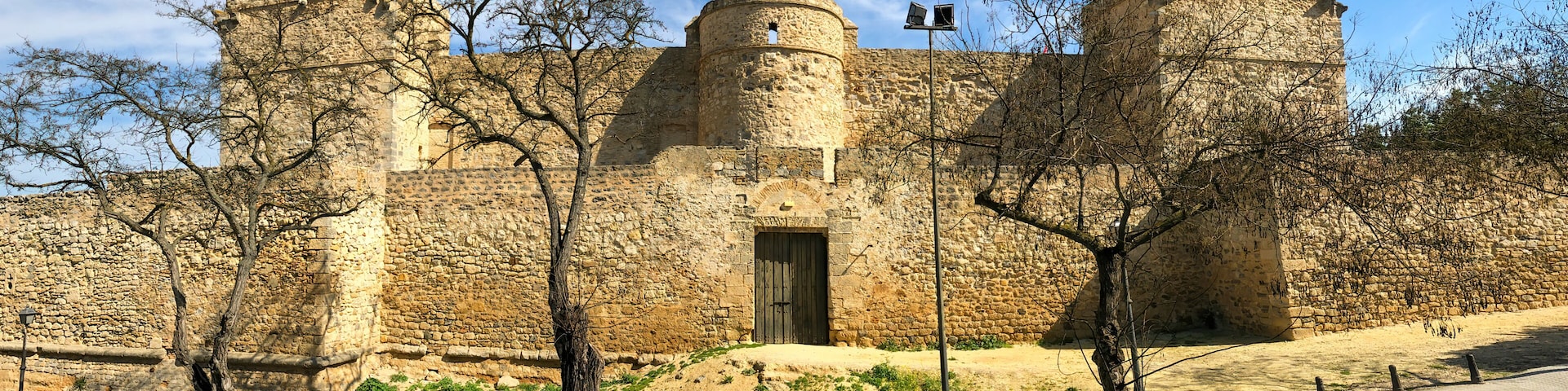 A historic stone castle with two towers, a central entrance, and a flagpole.
