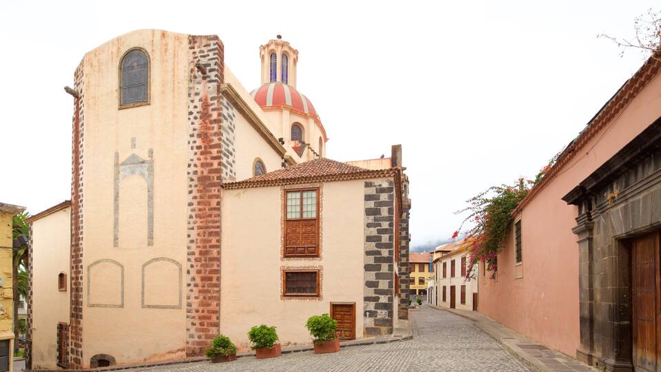 A historic church with a red dome and a bell tower, surrounded by cobblestone streets and traditional buildings.