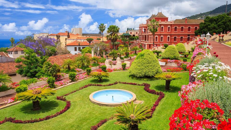 A well-manicured garden with a central fountain, surrounded by vibrant flowers and neatly trimmed hedges.