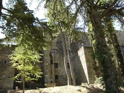 A stone building with a tall tree in front.