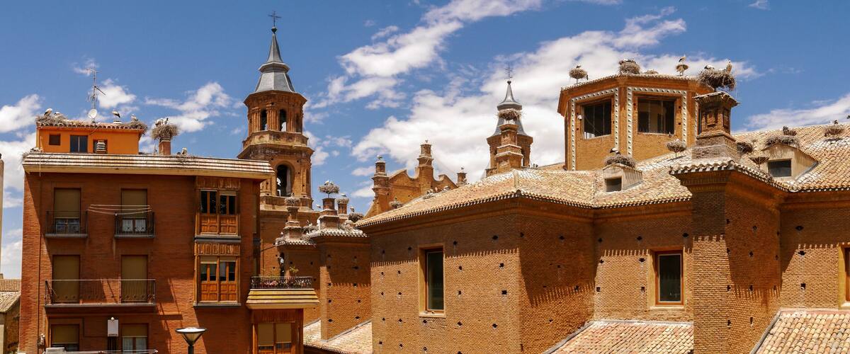 A historic building with ornate brickwork and multiple towers, including a prominent bell tower.