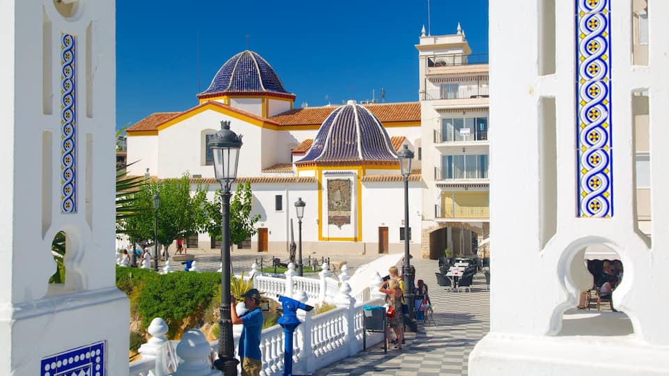 A white building with blue and yellow tiles, a blue dome, and a red-tiled roof.