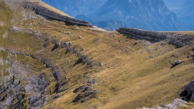 Un paisaje montañoso con terreno rocoso y laderas cubiertas de hierba.