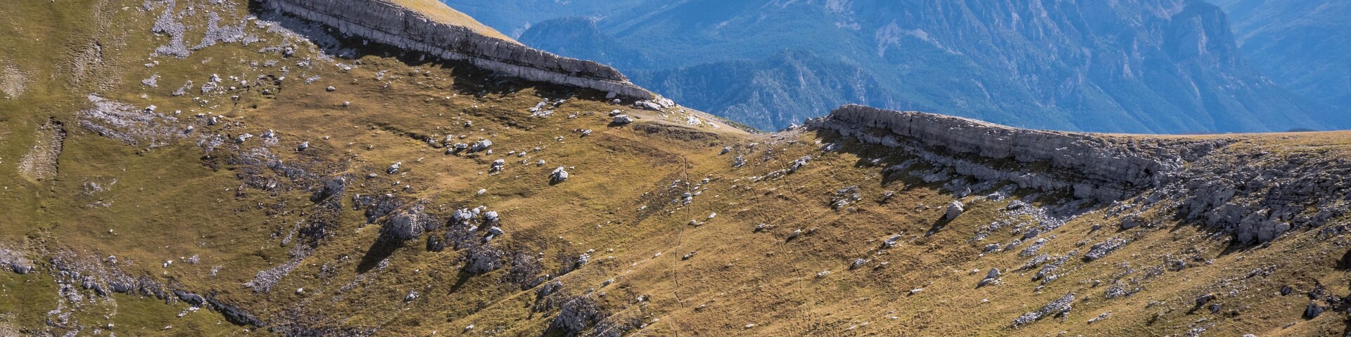 Un paisaje montañoso con terreno rocoso y laderas cubiertas de hierba.