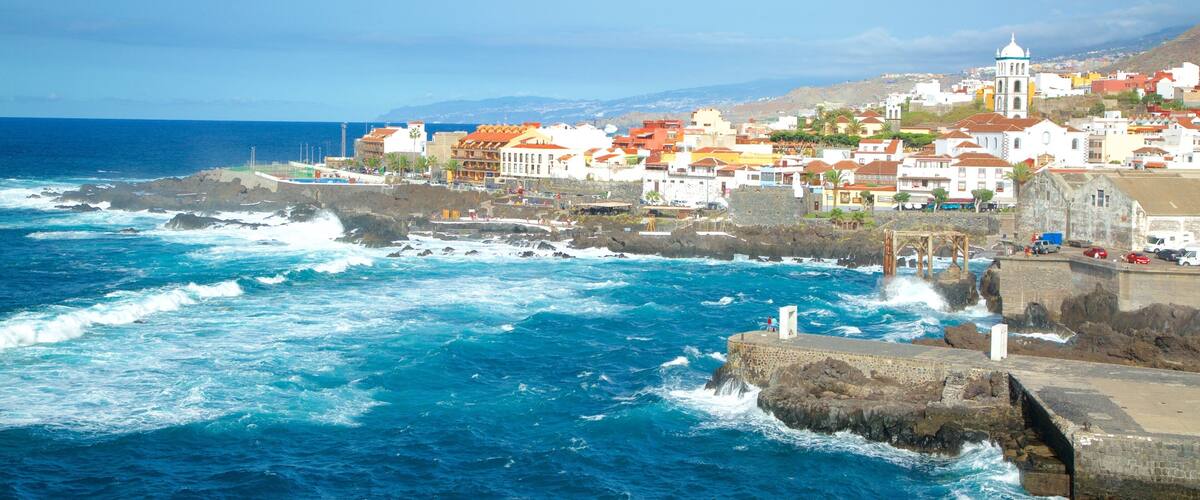 A coastal town with colorful buildings, rocky coastline, and waves crashing against the shore.