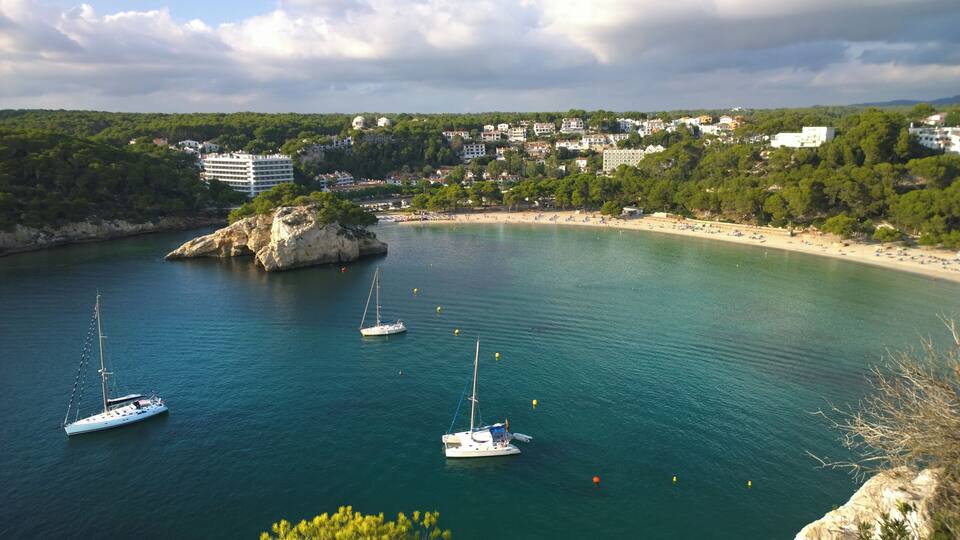 A coastal town with a bay, sailboats, and a rocky outcrop.