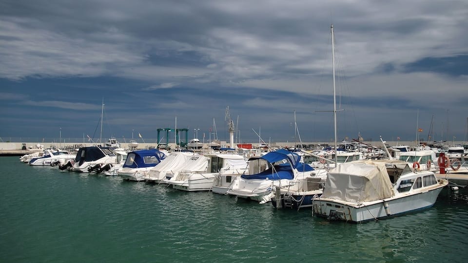 A marina with numerous boats docked under a cloudy sky.