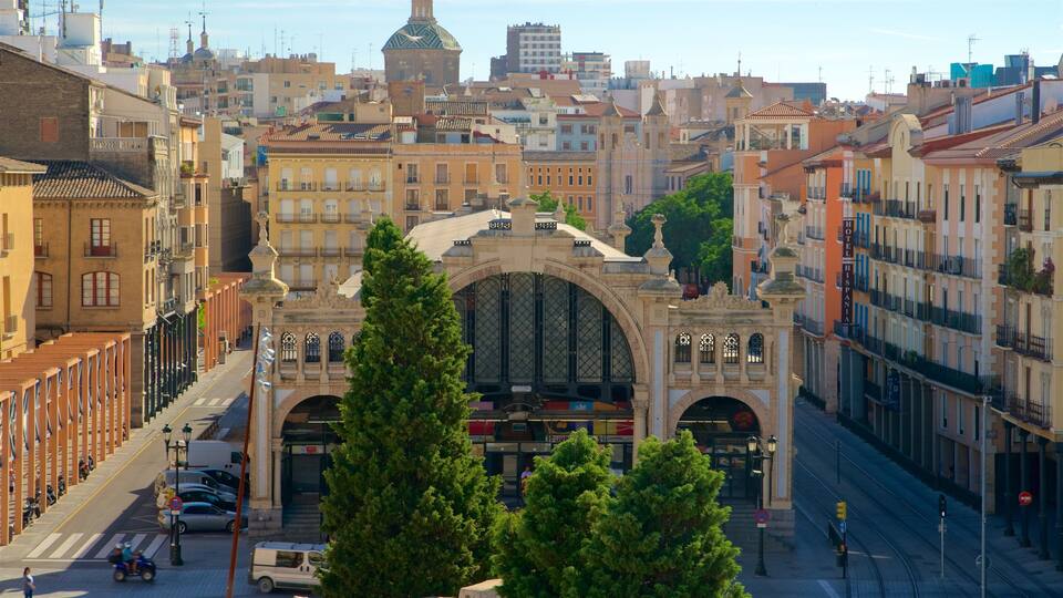A historic archway with intricate architecture, surrounded by urban buildings and trees.