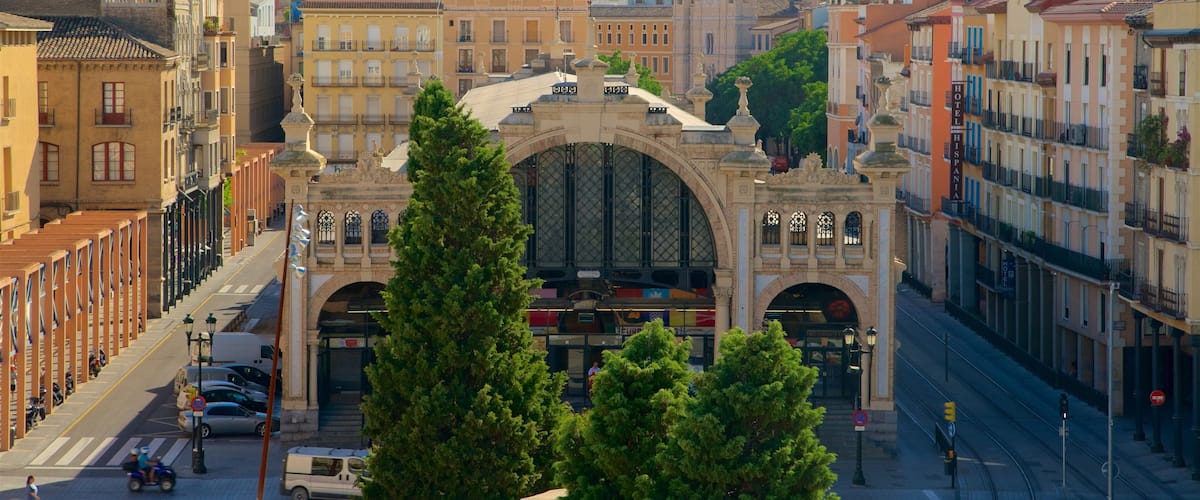 A historic archway with intricate architecture, surrounded by urban buildings and trees.