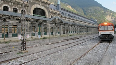 Estação de trem com várias plataformas e um trem se aproximando.