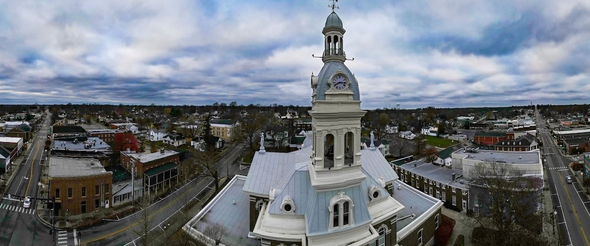 A town with a prominent clock tower, intersecting roads, and surrounding residential buildings.