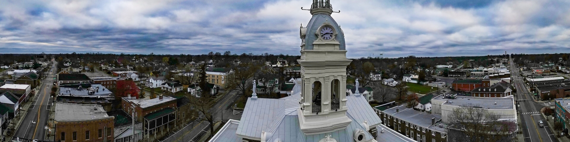 A town with a prominent clock tower, intersecting roads, and surrounding residential buildings.