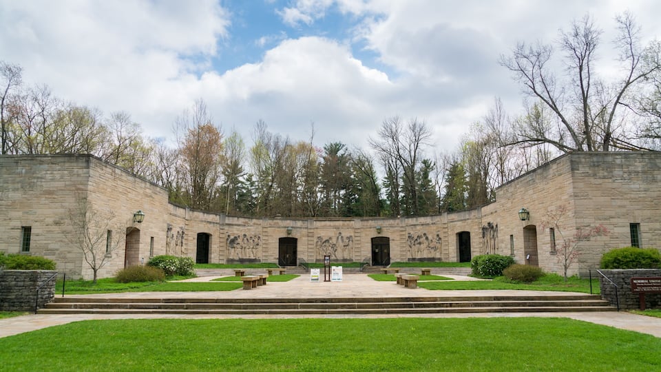 A historic stone building with murals, surrounded by a well-maintained lawn and trees.