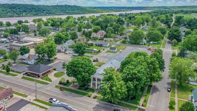 A suburban area with a river, green trees, and a mix of residential and commercial buildings.