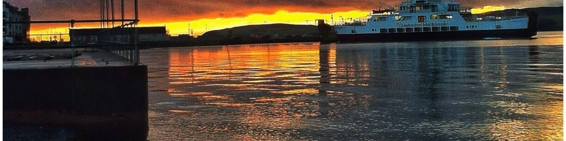 A sunset over a harbor with a boat named "Colebrook" reflecting on the water.