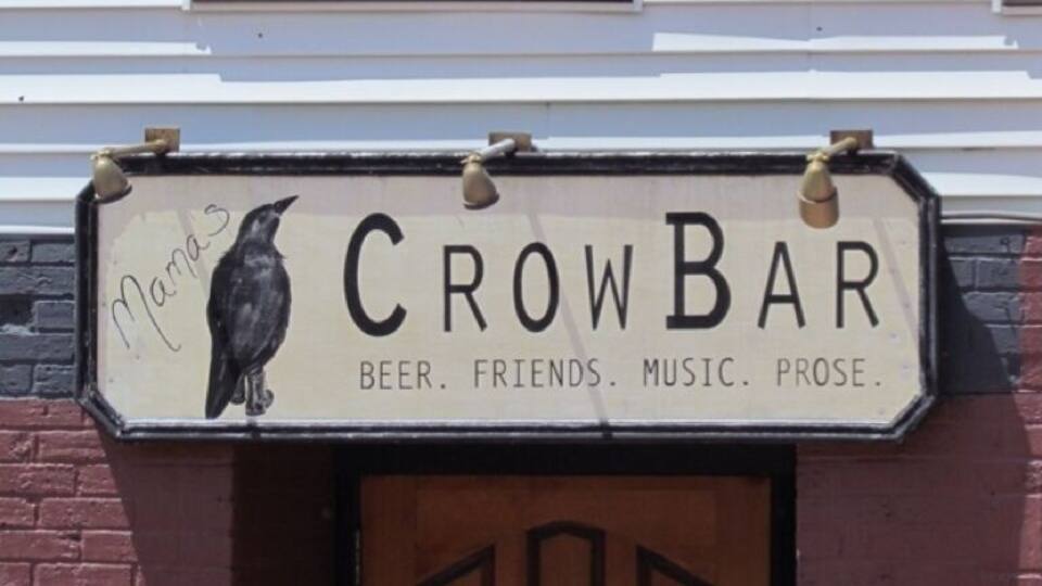 Cartell de 'CrowBar' amb una il·lustració d'un corb i referències a cervesa, amics, música i prosa.