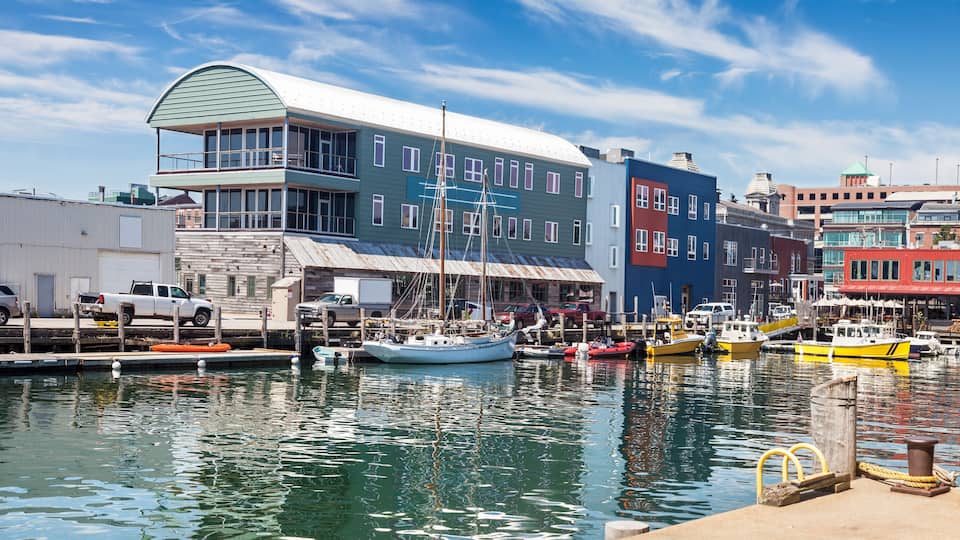 A harbor with boats, a white truck, and colorful buildings.
