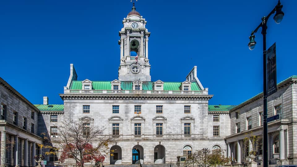 A historic building with a clock tower, green roof, and arched windows.