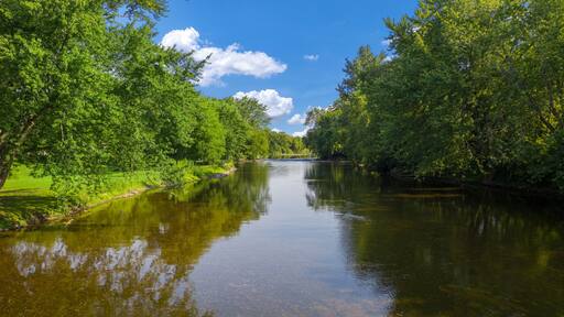 Beautiful clear river gentle blue skies and delightfully green trees. The Milwaukee River runs through Saukville WI