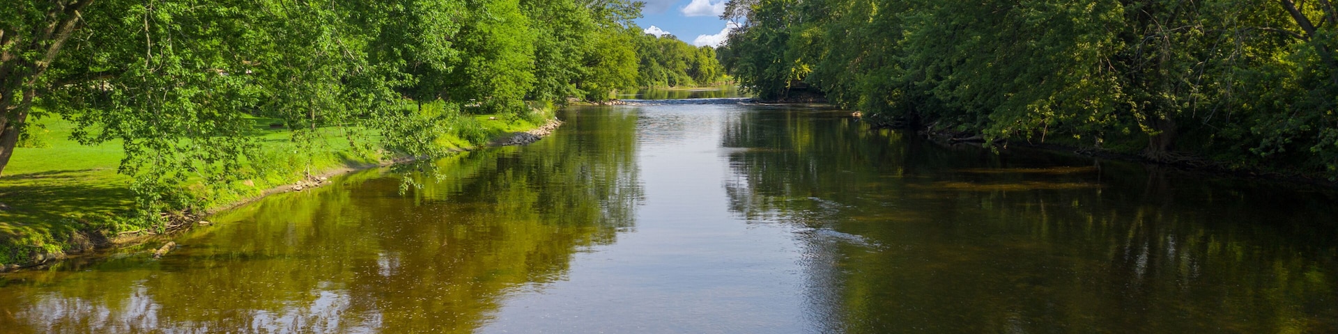 Beautiful clear river gentle blue skies and delightfully green trees. The Milwaukee River runs through Saukville WI