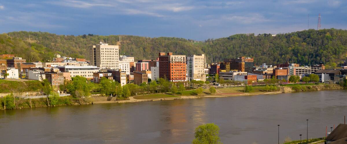 A river flowing through a city with buildings and hills in the background.