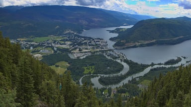 Un lago rodeado de montañas, un pueblo y bosques densos.