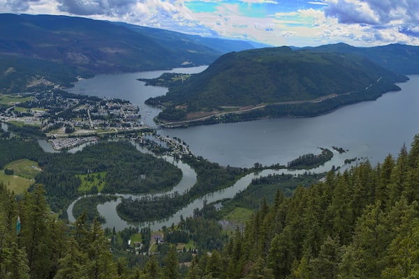 A lake surrounded by mountains, a town, and dense forests.