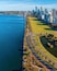 A coastal cityscape with a long promenade along the waterfront, a park, and modern high-rise buildings.