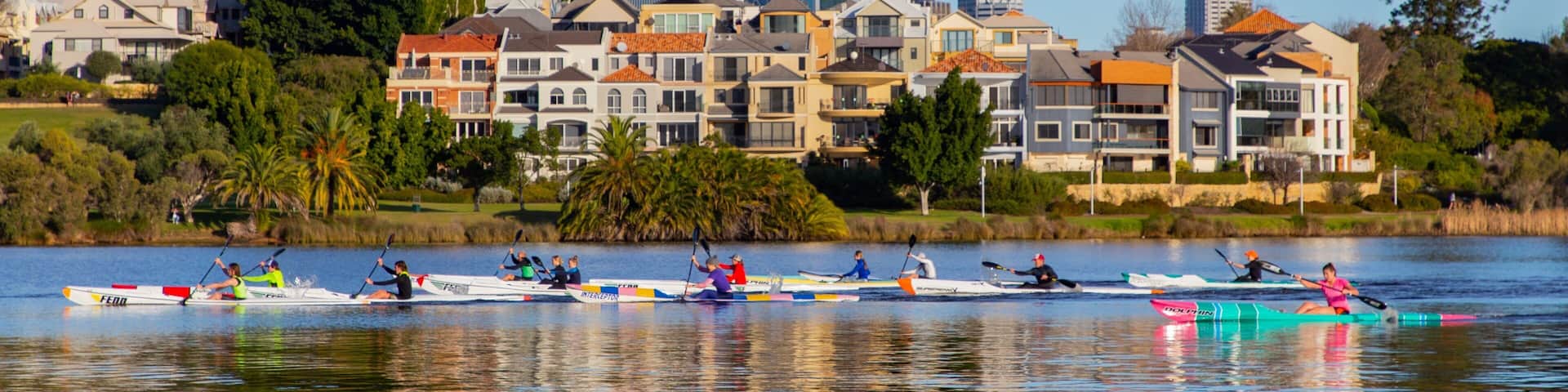 A waterfront with rowing boats and a cityscape in the background.