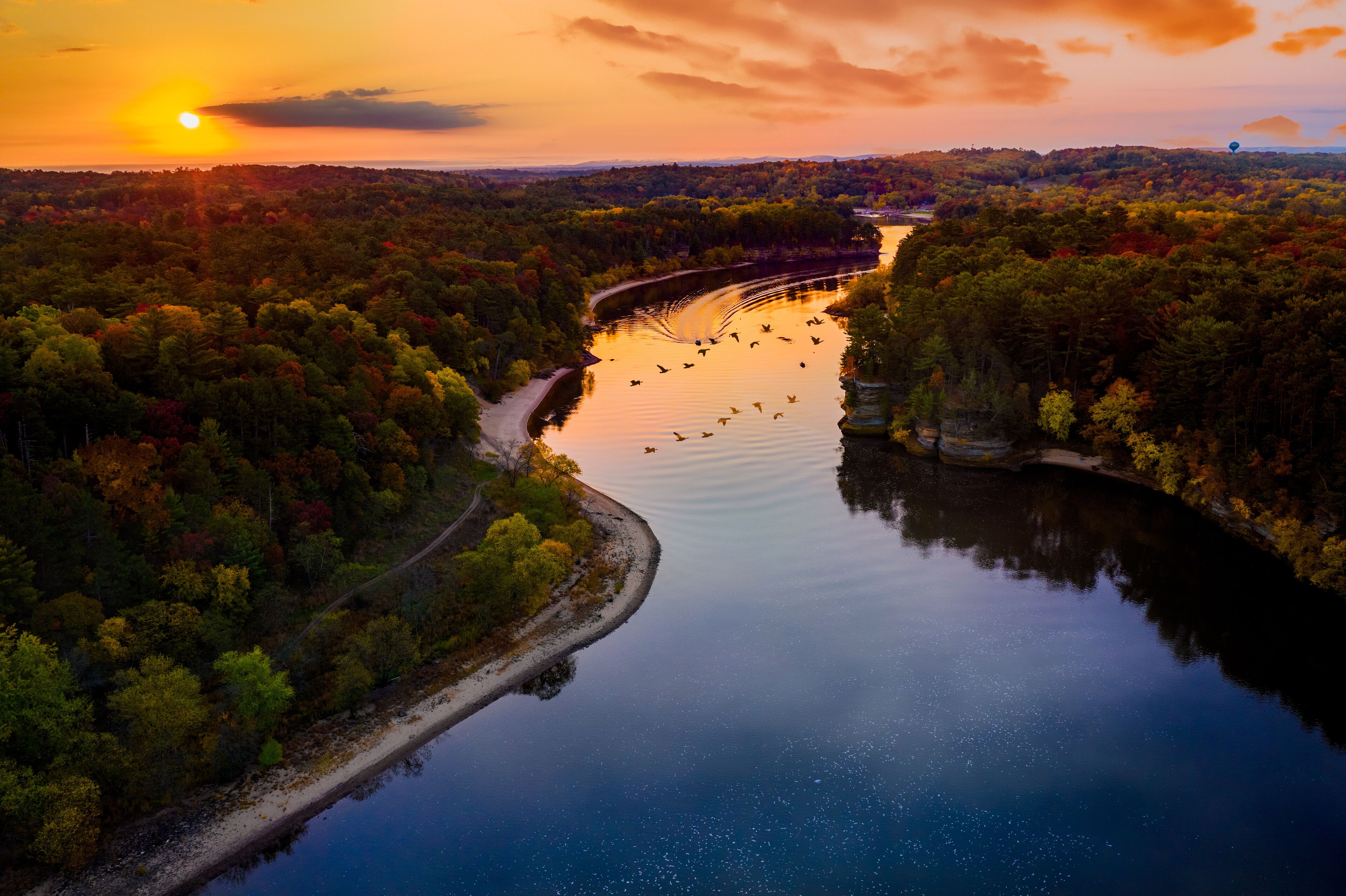 A river winding through a forest at sunset.