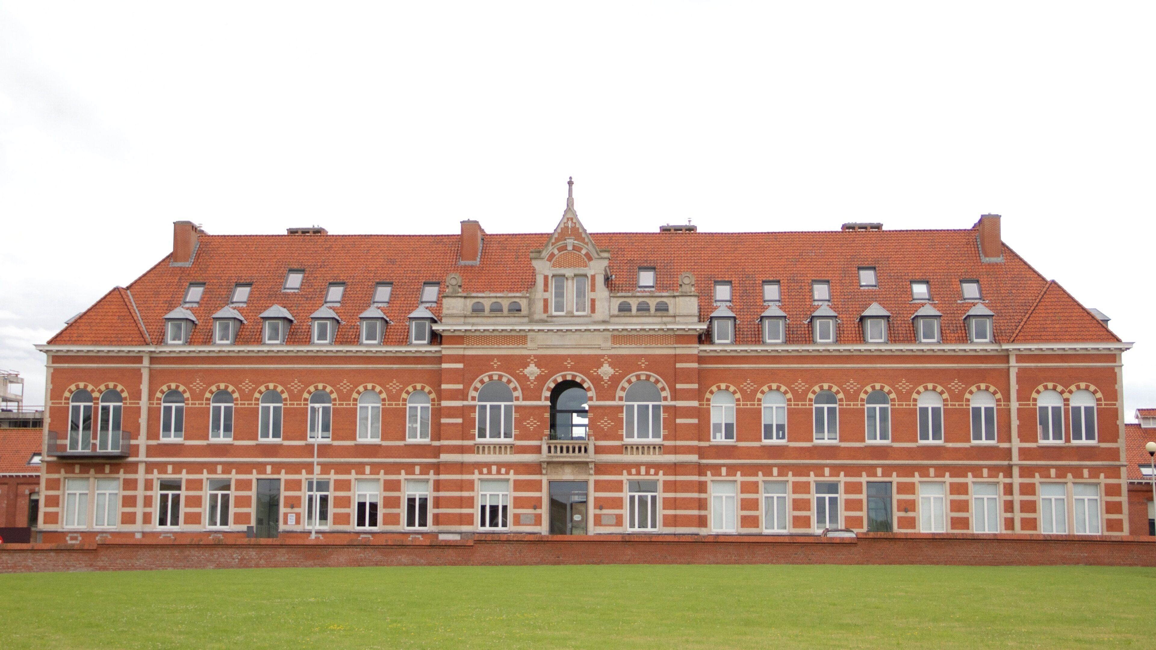 A large red-brick building with a symmetrical facade, multiple windows, and a central entrance.