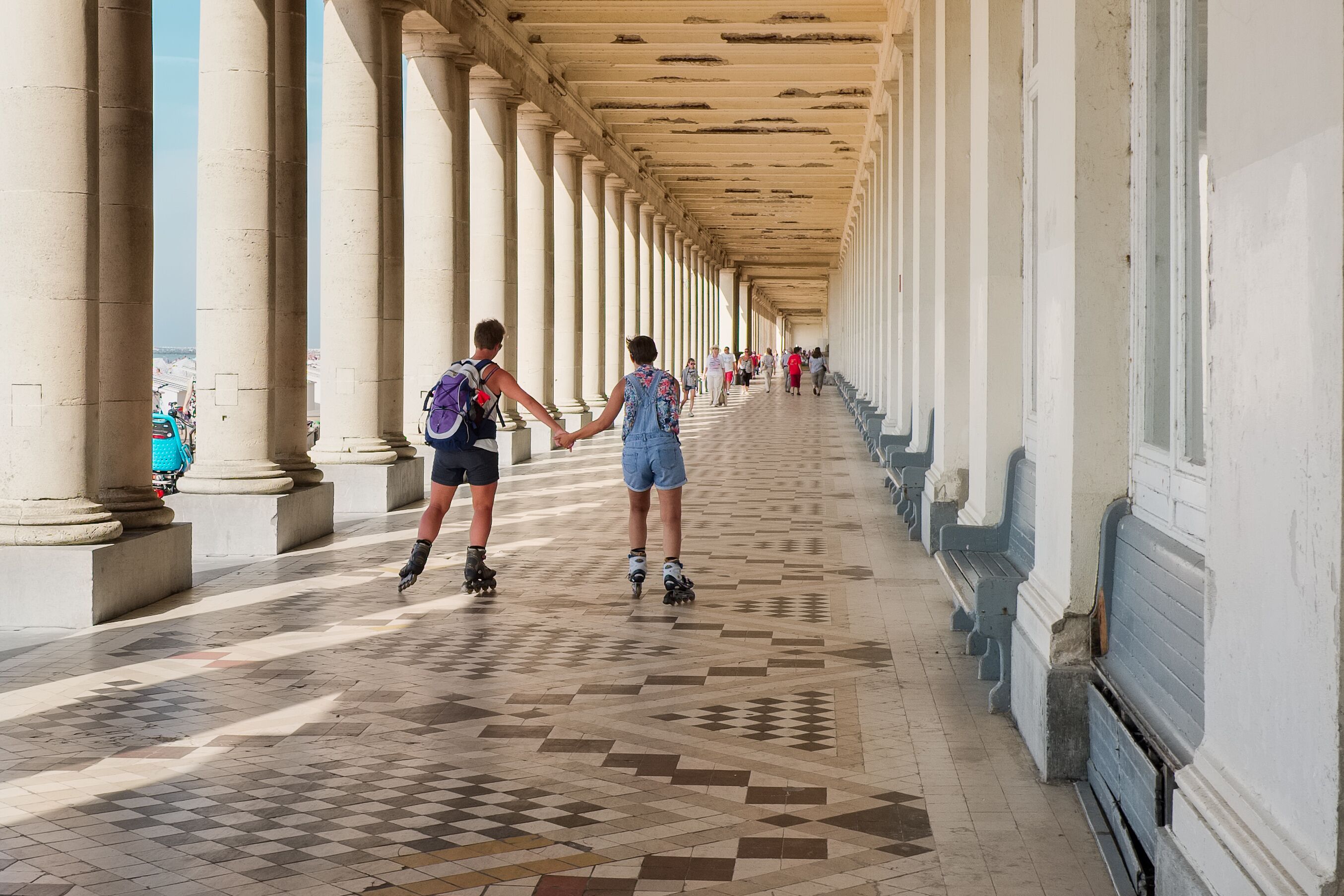 Un pasillo cubierto con columnas y piso estampado.