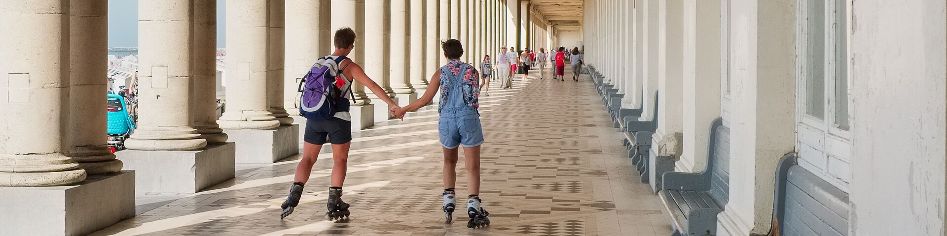 Un pasillo cubierto con columnas y piso estampado.