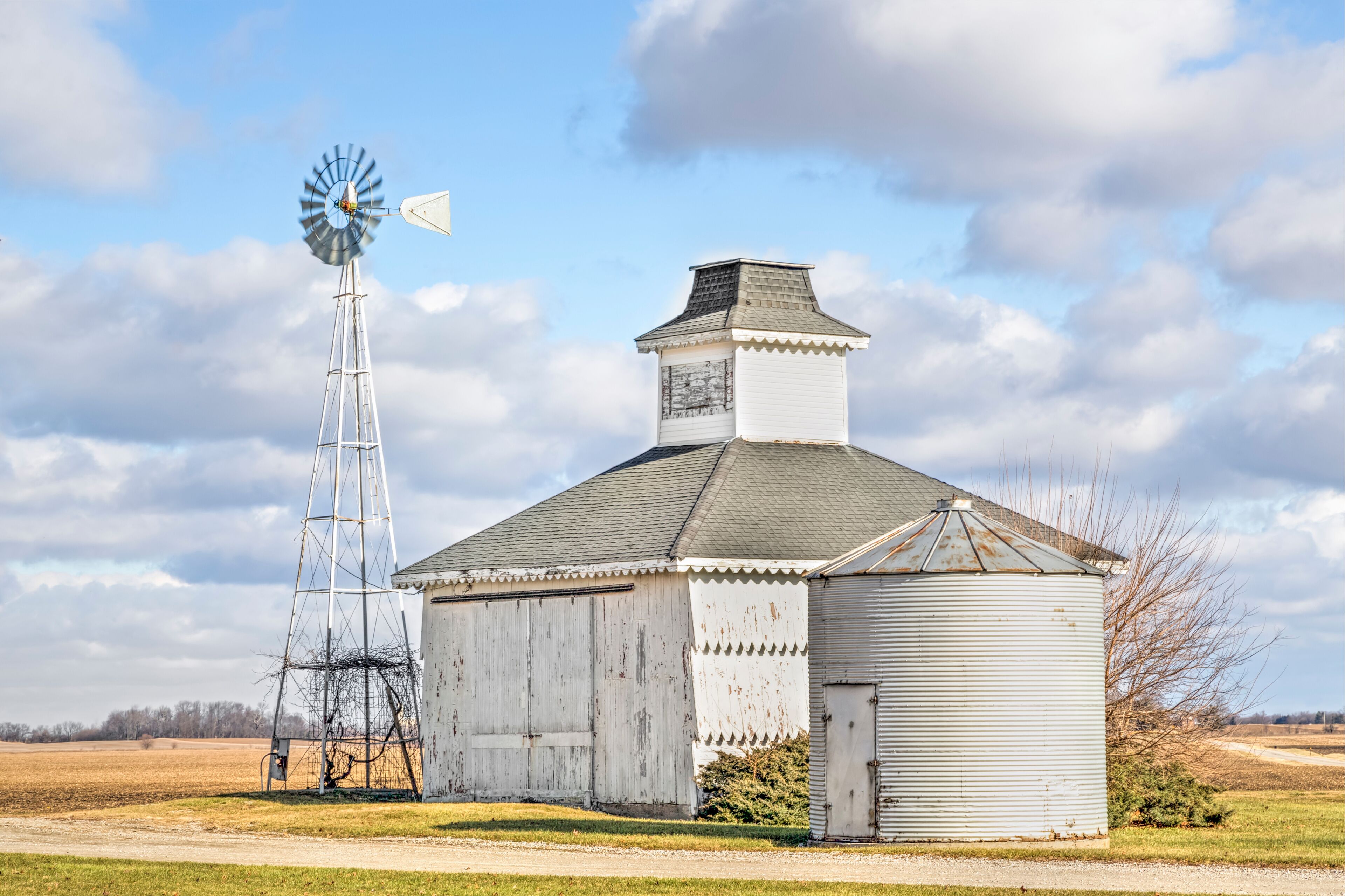 A windmill and a barn in a rural setting.